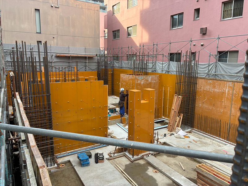 鉄筋コンクリート造(RC造)の建設現場で、壁や柱の型枠を組み立てる職人